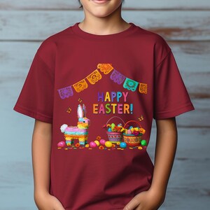 K&ouml;nnte beinhalten: Burgunderfarbenes T-Shirt mit einem farbenfrohen Osterdesign. Die Grafik zeigt einen Pi&ntilde;ata-Hasen, K&ouml;rbe mit Eiern und die Worte "HAPPY EASTER!". Ein festliches Banner mit ausgeschnittenen Formen h&auml;ngt &uuml;ber dem Text.