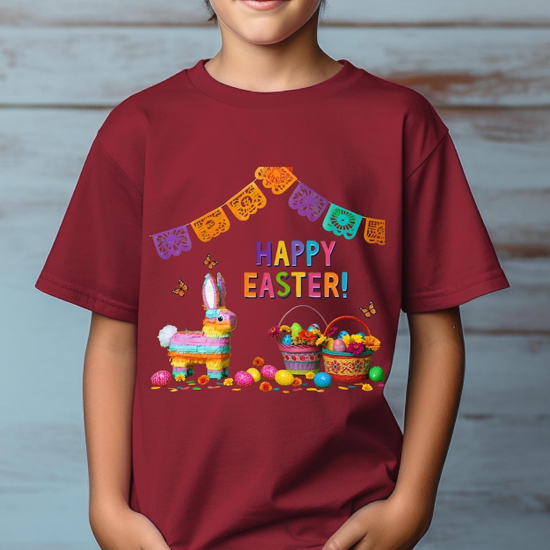 K&ouml;nnte beinhalten: Burgunderfarbenes T-Shirt mit einem farbenfrohen Osterdesign. Die Grafik zeigt einen Pi&ntilde;ata-Hasen, K&ouml;rbe mit Eiern und die Worte "HAPPY EASTER!". Ein festliches Banner mit ausgeschnittenen Formen h&auml;ngt &uuml;ber dem Text.