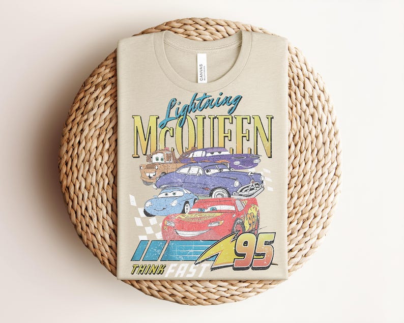 Puede incluir: Camiseta color beige con un dise&ntilde;o de Rayo McQueen y otros personajes de Cars. El dise&ntilde;o incluye el texto "Lightning McQueen" y "95", con la frase "Think Fast" en la parte inferior. La camiseta est&aacute; hecha de un material suave.