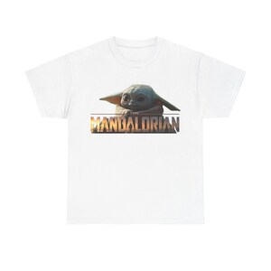 A white t-shirt with a graphic design featuring the character Baby Yoda from the Star Wars series The Mandalorian.