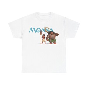 A white t-shirt with a graphic design featuring two cartoon characters, one of which is a woman and the other is a man. The text "Moana" is displayed above the characters.