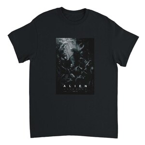 Könnte beinhalten: Ein schwarzes T-Shirt mit kurzen Ärmeln und einem rechteckigen Grafikdruck auf der Brust. Der Druck zeigt eine dunkle, monochrome Szene mit dem Text ALIEN ROMULUS und MAY 16 in weißen Großbuchstaben am unteren Rand der Grafik.