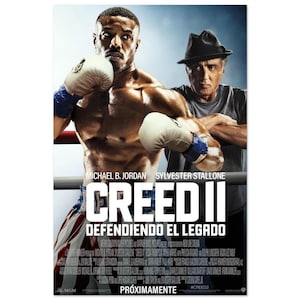 Op de afbeelding: Een filmposter voor Creed II met een bokser zonder shirt, witte handschoenen en een rood-wit-blauwe broek. Achter hem staat een man in een grijs t-shirt en een zwarte hoed. De titel CREED II en de tekst zijn duidelijk op de poster te zien.