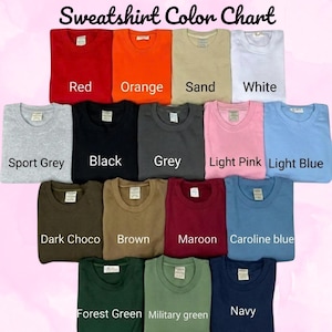 Op de afbeelding: Een kleurenkaart voor sweatshirts met vijftien opgevouwen sweatshirts met ronde hals in verschillende kleuren, waaronder rood, oranje, zand, wit, sportgrijs, zwart, grijs, lichtroze, lichtblauw, donkerchocolade, bruin, bordeaux, carolineblauw, bosgroen, militair groen en marineblauw.