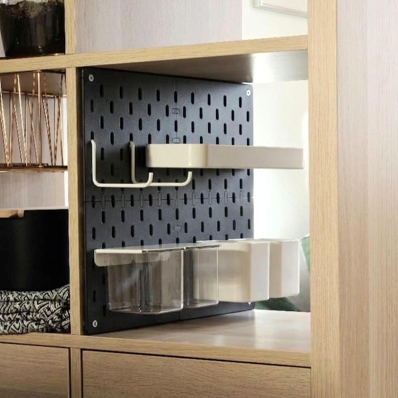 Schwarze Lochplatte aus mattem PLA in einem hellen Holzregal mit verschiedenen weißen Halterungen und durchsichtigen Behältern.