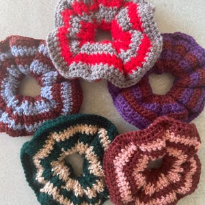 Può includere: Cinque scrunchies all'uncinetto fatti a mano in vari colori. Gli scrunchies includono rosso e grigio, viola e bordeaux, verde e beige, bordeaux e rosa e bordeaux e blu. Questi accessori per capelli sono perfetti per aggiungere un tocco di colore a qualsiasi acconciatura.