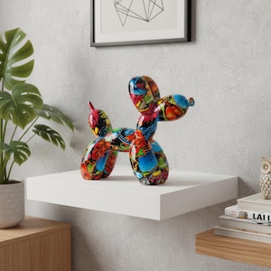Peut inclure: Une sculpture de chien ballon colorée avec une finition brillante. La sculpture présente un mélange vibrant de motifs rouges, bleus, jaunes et verts. Elle est exposée sur une étagère blanche, ajoutant une touche artistique à tout espace.