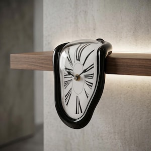 Puede incluir: Un reloj negro y blanco con números romanos, que parece derretirse sobre una estantería de madera. La esfera del reloj es blanca con números y manecillas negras, y el marco es negro. Un objeto decorativo único.
