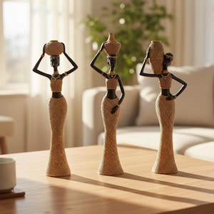 Puede incluir: Tres figuras altas y esbeltas que representan personajes de piel oscura, cada uno con un top y una falda larga de color beige con textura. Cada figura lleva un recipiente de color beige de distinta forma sobre la cabeza o el hombro.