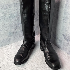 Botas de montar vintage de cuero negro con caña alta, estilo ecuestre clásico.