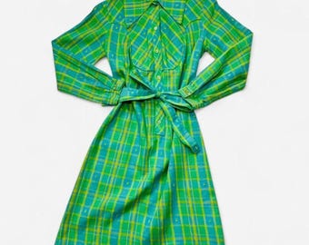 May include: A long-sleeve knee-length dress featuring a vibrant green and yellow plaid pattern. The garment includes a pointed collar, a button-down front placket, and a matching fabric tie belt at the waist to cinch the silhouette.