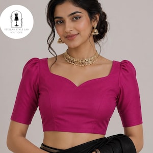 May include: A magenta blouse featuring a sweetheart neckline and short puff sleeves. The garment is paired with a gold-toned choker necklace and matching drop earrings. A circular logo in the upper left corner displays the text STELLAR STYLE LAB BOUTIQUE.