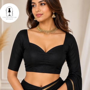 May include: A black blouse featuring a sweetheart neckline and elbow-length sleeves, paired with a gold fringe choker necklace and gold-toned drop earrings. The garment is solid black with a smooth texture, and a circular logo reads STELLAR STYLE LAB BOUTIQUE.