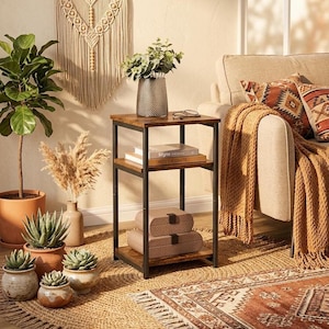 May include: A three-tier side table with a dark wood grain finish and a black metal frame. The table features a square top, a middle shelf holding two books titled Style and Arts the Crafts, and a bottom shelf holding two stacked rectangular boxes.
