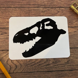 May include: Black silhouette of a dinosaur skull on a white background.