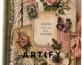 Op de afbeelding: Een decoratieve journal-kaft met een collage van vintage bloemenillustraties, een vlinder, kanten rand en een roze lint. De tekst in het midden luidt BLOOM where you are PLANTED. Andere elementen zijn postzegels, papierresten en een metalen labelhouder.