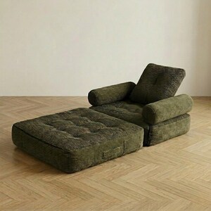 Olive green corduroy single-seater futon armchair partially unfolded into a chaise lounge or bed configuration against a plain white wall on a light herringbone parquet floor. The mattress section is fully extended forward while the back cushion and rounded armrests remain upright, clearly demonstrating the conversion from armchair to single bed. The deep tufted wide-ribbed corduroy surface and layered base structure are visible. A practical and stylish space-saving convertible armchair bed.