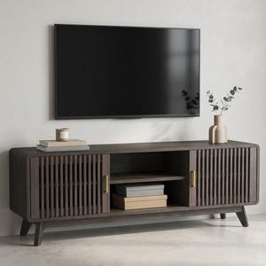 May include: A dark gray wooden TV stand with a slatted door design and gold-colored handles. The stand has a mid-century modern style with angled legs. A black television is mounted above the stand, with a vase and candle on top.