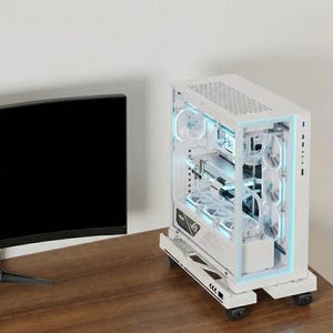 May include: A white computer case with a transparent side panel, showcasing internal components. The case has a rectangular shape with a top vent and is mounted on a wheeled base. Blue LED lights illuminate the interior, and a black monitor is visible on the left.