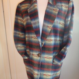 May include: A long-sleeved blazer with a southwestern-inspired pattern in shades of blue, red, green, and cream. The blazer has a single button closure and two pockets.