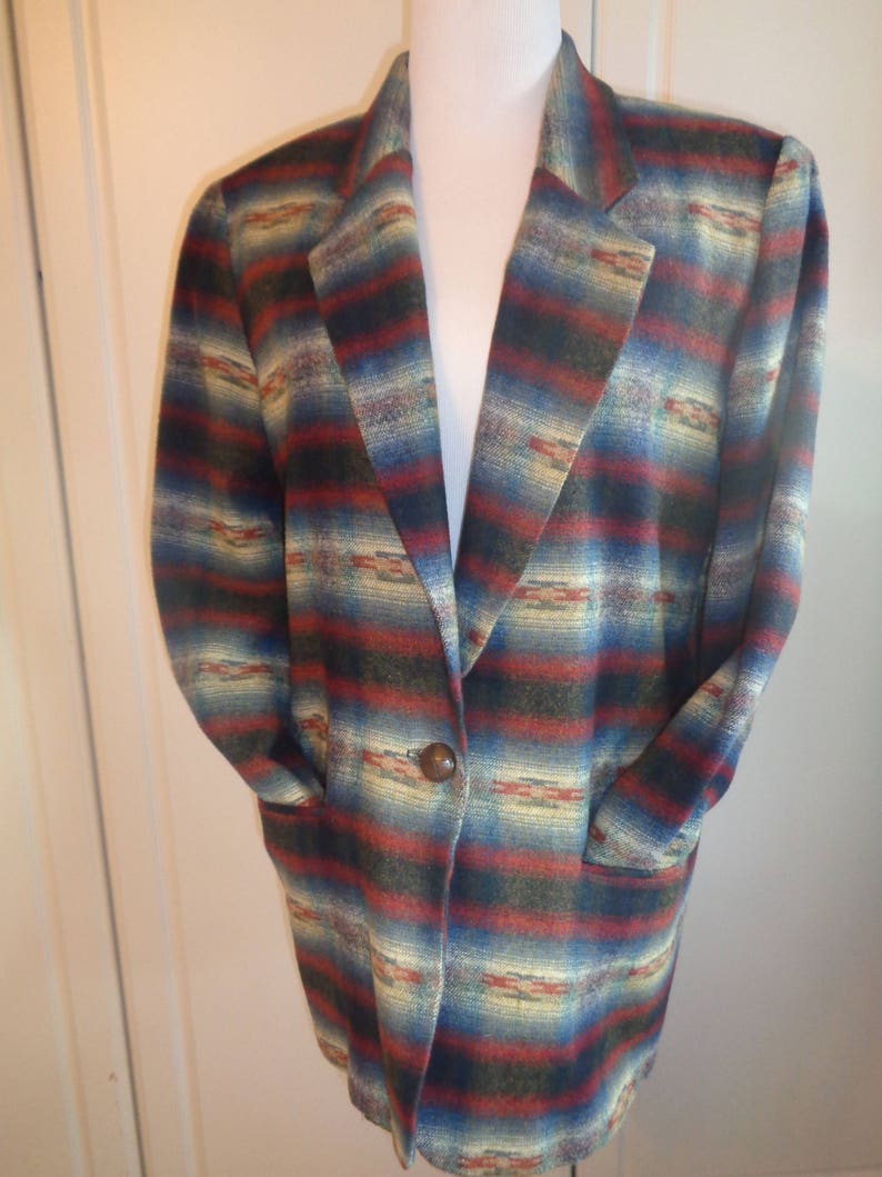 May include: A long-sleeved blazer with a southwestern-inspired pattern in shades of blue, red, green, and cream. The blazer has a single button closure and two pockets.