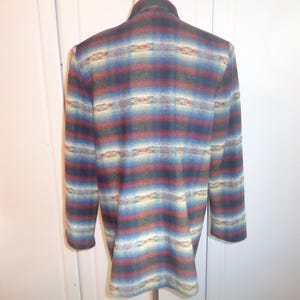 May include: A long-sleeved, multi-colored blazer with a southwestern-inspired pattern. The blazer has a dark blue, red, and cream color scheme with a geometric design.