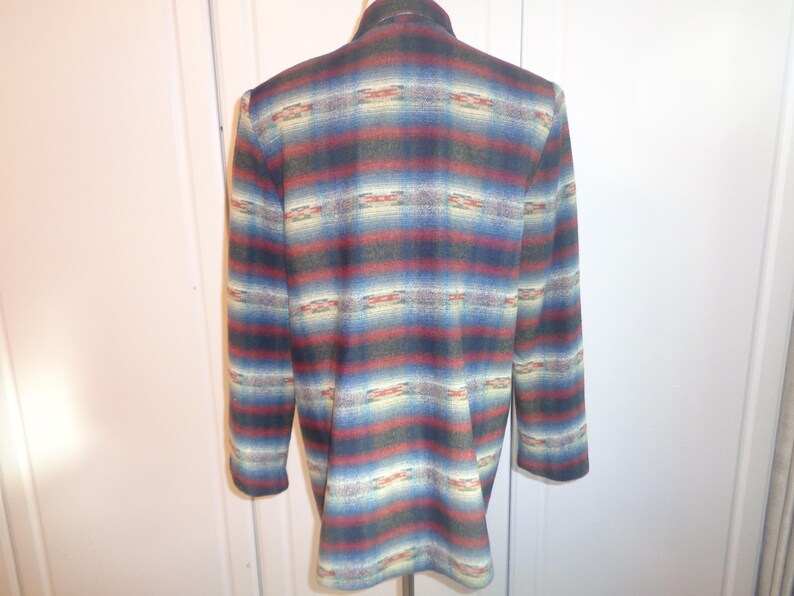 May include: A long-sleeved, multi-colored blazer with a southwestern-inspired pattern. The blazer has a dark blue, red, and cream color scheme with a geometric design.