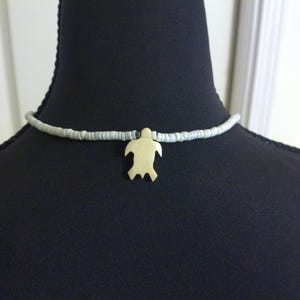 May include: A light blue beaded necklace with a gold turtle pendant.