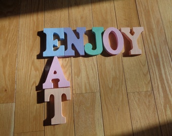 Hand Painted Sign for a kitchen or dining room that spell out Enjoy and Eat or Eat and Enjoy in a soft pastel color palette on wood letters