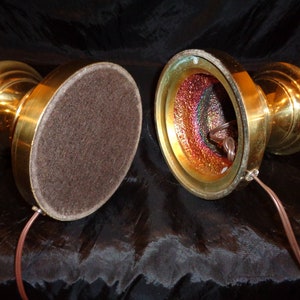 May include: Two vintage brass candlestick lamps with a warm, golden finish. The lamps have a classic, ornate design with a round base covered in brown felt. The interior of the lamp base has a colorful, iridescent finish, and a brown electrical cord.