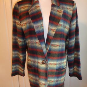 May include: A long-sleeved blazer with a southwestern-inspired pattern in shades of red, blue, green, and beige. The blazer has a single button closure and two pockets.