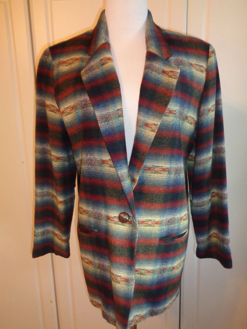 May include: A long-sleeved blazer with a southwestern-inspired pattern in shades of red, blue, green, and beige. The blazer has a single button closure and two pockets.