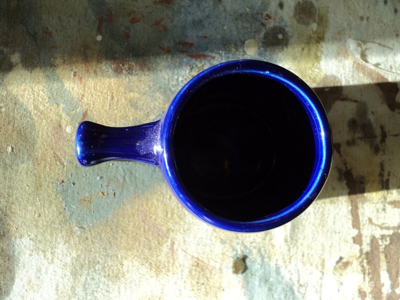 May include: A deep blue ceramic mug with a handle. The mug is empty and the inside is visible.