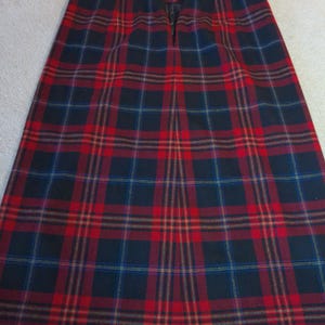 May include: A red, black, and yellow plaid skirt with a zipper closure in the back.