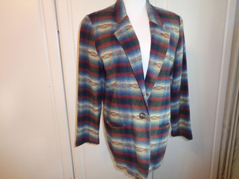 May include: A striped blazer with a southwestern pattern in shades of blue, red, and yellow. The blazer has a single button closure and two pockets.