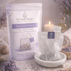 May include: A "Sui Soak House" botanical bath ritual product, with "Sleep and Relax" text. A single tea bag is in a small white bowl. The image includes a lit candle, lavender, and other bath products.