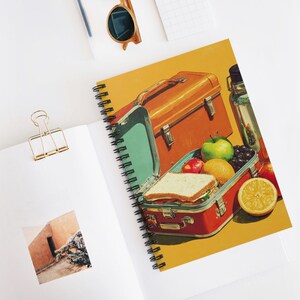 Peut inclure: Cahier à spirales avec une illustration rétro d'une boîte à lunch remplie de fruits et d'un sandwich. Le cahier a un fond jaune et une esthétique vintage. Une bouteille d'eau et une deuxième boîte à lunch sont également visibles.