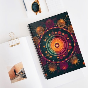 May include: Spiral-bound notebook with a colourful mandala design. The cover displays an intricate pattern with orange, purple, and gold details on a dark teal backdrop. The notebook is open, showing blank pages and a photograph.