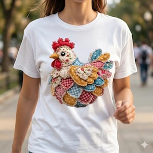 May include: White t-shirt featuring a colorful, patchwork-style chicken design. The chicken has a red comb and wattle, a yellow beak, and a body made of various patterned fabrics in shades of red, blue, yellow, and pink. The design is centered on the shirt.