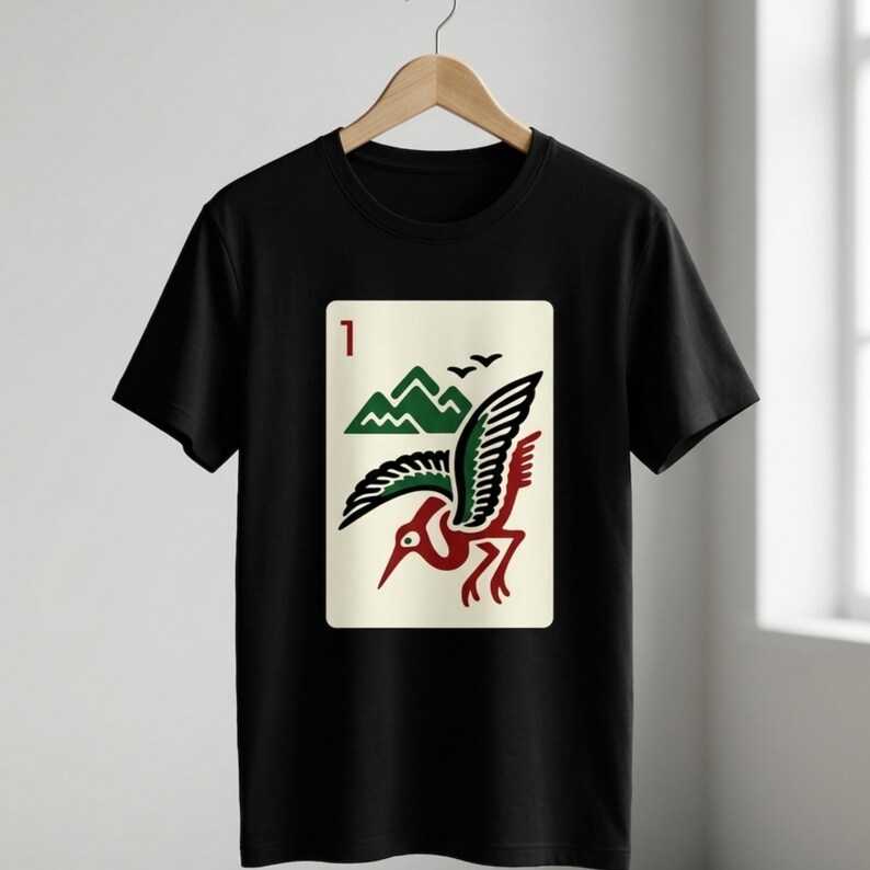 Puede incluir: Camiseta negra con un dise&ntilde;o gr&aacute;fico de un p&aacute;jaro, monta&ntilde;as y el n&uacute;mero 1. El p&aacute;jaro es rojo, verde y negro, sobre un fondo crema. El dise&ntilde;o recuerda a una carta de juego.