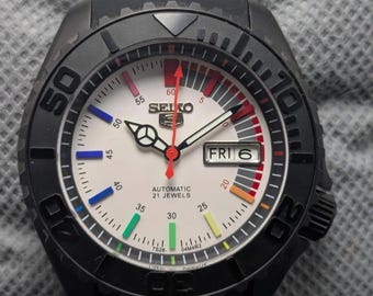 Reloj deportivo vintage Seiko 5 automático con esfera blanca y bisel negro para hombre.
