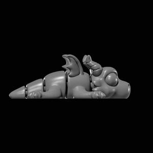 May include: A matte gray articulated dragon figurine featuring a segmented body, small wings, and a head with two horns. The creature is depicted in a resting, prone position with its limbs tucked close to its body, showcasing a smooth surface.