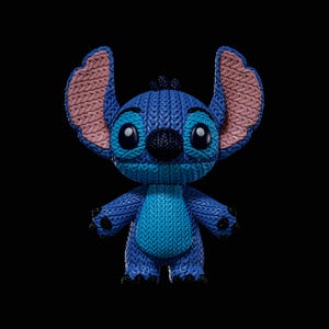 Puede incluir: Una figura estilizada del personaje Stitch, con una superficie texturizada que imita un patrón de lana tejida en azul y azul claro. La figura tiene orejas grandes y erguidas con secciones interiores rosas, una nariz oscura y ojos negros.