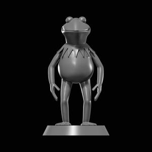 May include: A monochromatic grey figurine of a frog character with a rounded body, thin limbs, and a pointed collar. The figure stands upright on a smooth, trapezoidal base against a solid black background, featuring a wide, smiling mouth.