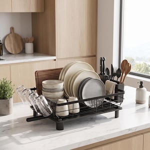 Pode incluir: Um escorredor de pratos de metal preto contendo vários pratos cor de creme, tigelas cinzentas, copos transparentes e uma tábua de cortar de madeira. Inclui um suporte preto para utensílios com facas, garfos, colheres e colheres de pau.