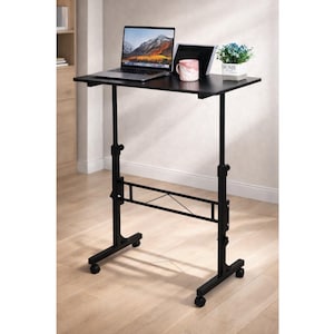 May include: A black adjustable laptop desk with a rectangular tabletop. A laptop, tablet, and mug are on the desk. The desk has a black metal frame with wheels for mobility. The height is adjustable.