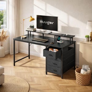 May include: A black computer desk with a monitor displaying the word "Huuger". The desk has a keyboard, a yellow desk lamp, and a three-drawer cabinet. A round woven rug is on the floor.
