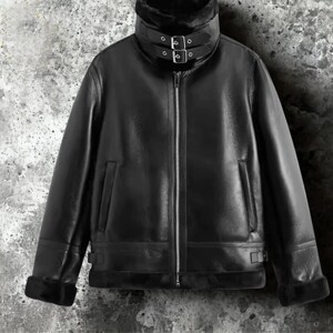 May include: Black leather jacket with a high collar and a faux fur lining. The jacket features a zipper closure, two front pockets, and adjustable buckles on the collar and cuffs. A classic outerwear piece.