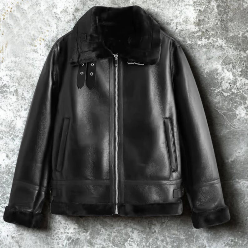 May include: A black leather jacket with a shearling collar and lining. The jacket features a zip-up front, two front pockets, and buckle details on the collar and cuffs. The jacket is a classic style.