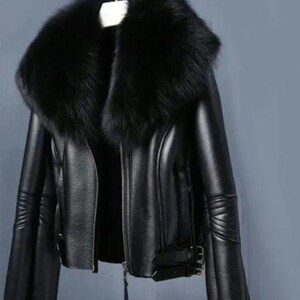 May include: A black leather jacket with a large, fluffy black fur collar. The jacket has a zipper closure, flared sleeves, and buckle details. The jacket is hanging on a hanger.
